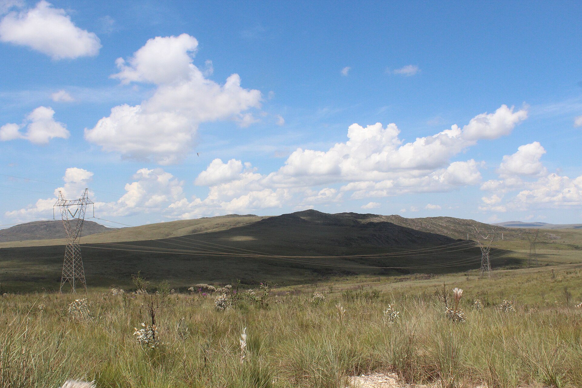 Torres e linhas de transmissão atravessando um campo na serra